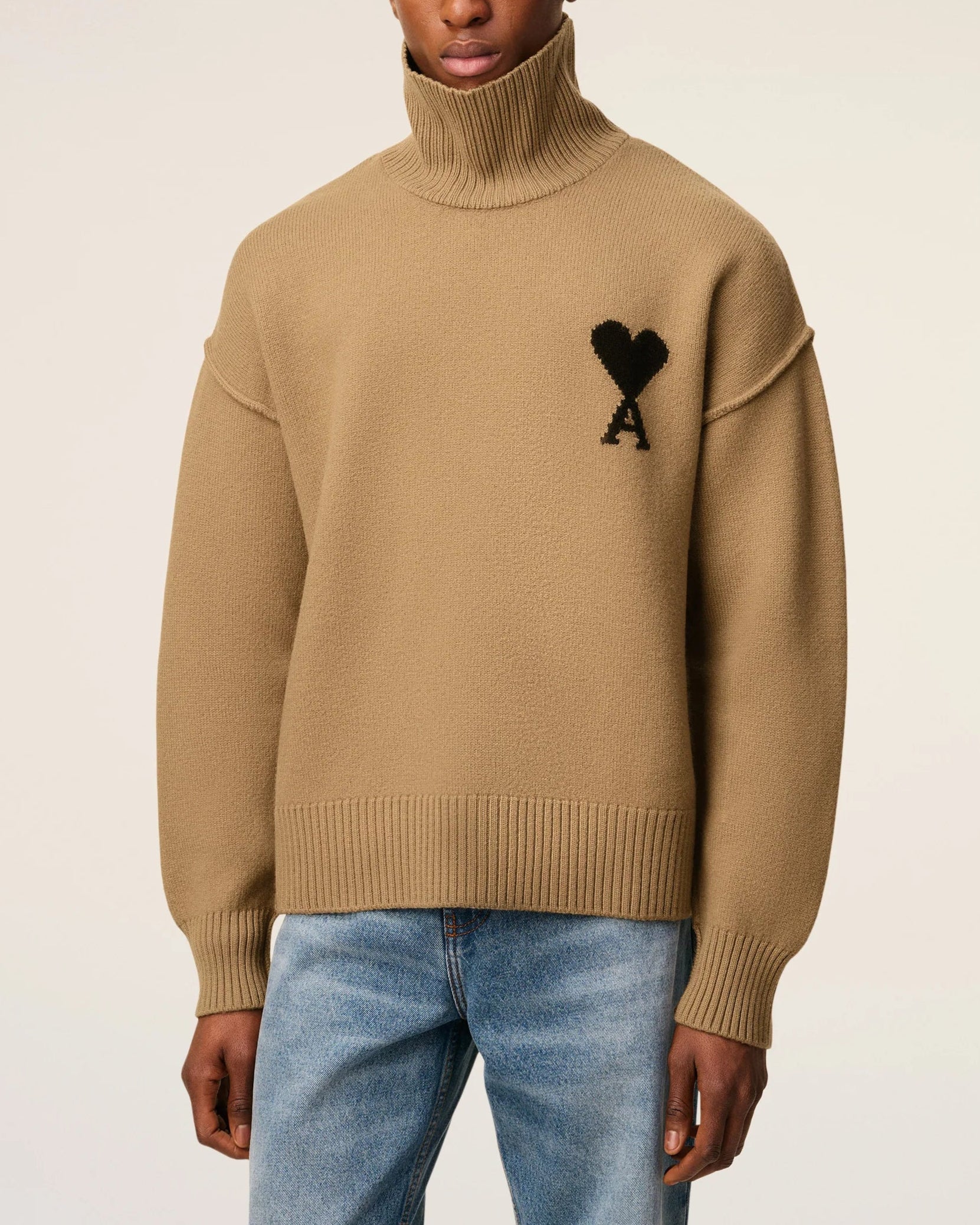 Beige turtleneck sweater with black heart and letter 'A' design on a beige background