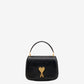 Black handbag with a gold heart and arrow design on a beige background