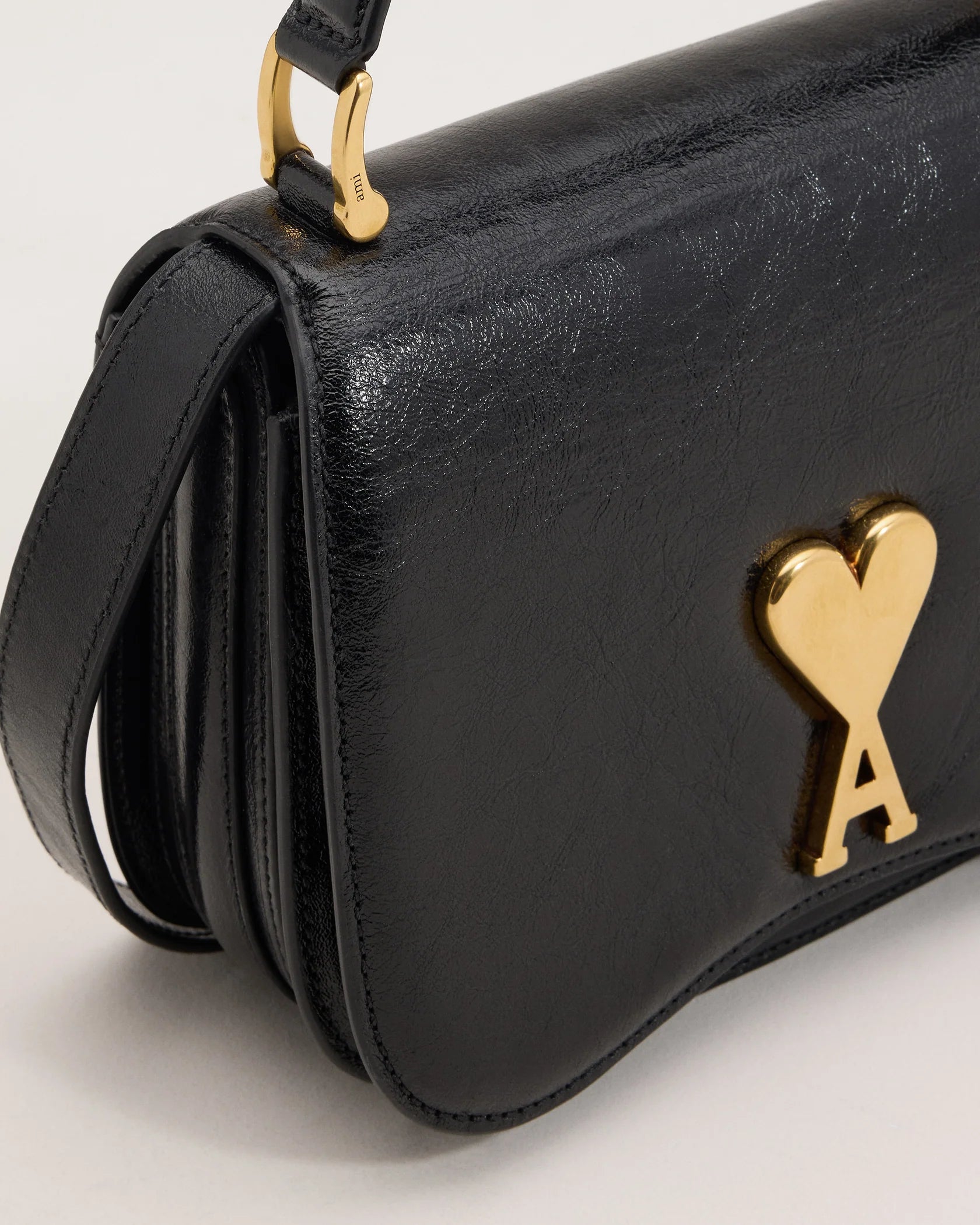 Black handbag with a gold heart and arrow design on a beige background