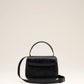 Black handbag with a gold heart and arrow design on a beige background