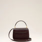 Burgundy handbag with a gold heart and letter 'A' emblem on a beige background