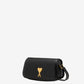 Black handbag with a gold heart emblem on a beige background