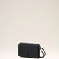 Person holding a black handbag against a neutral background