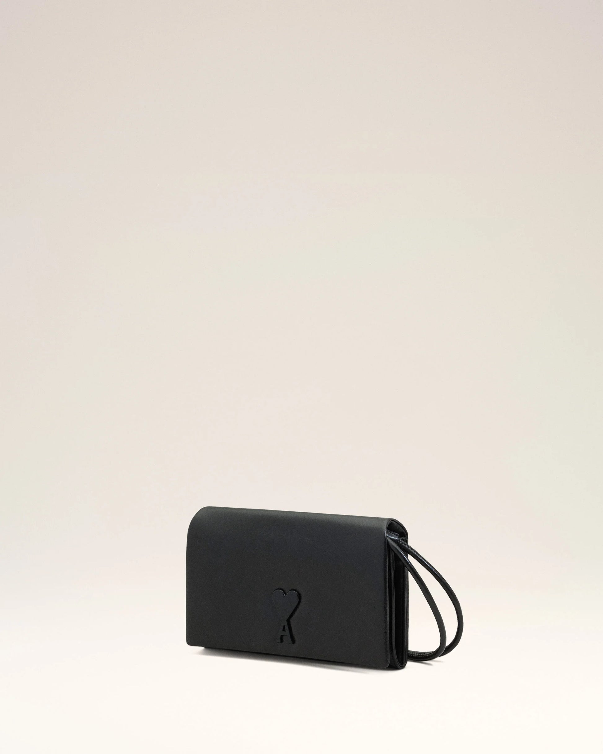 Person holding a black handbag against a neutral background