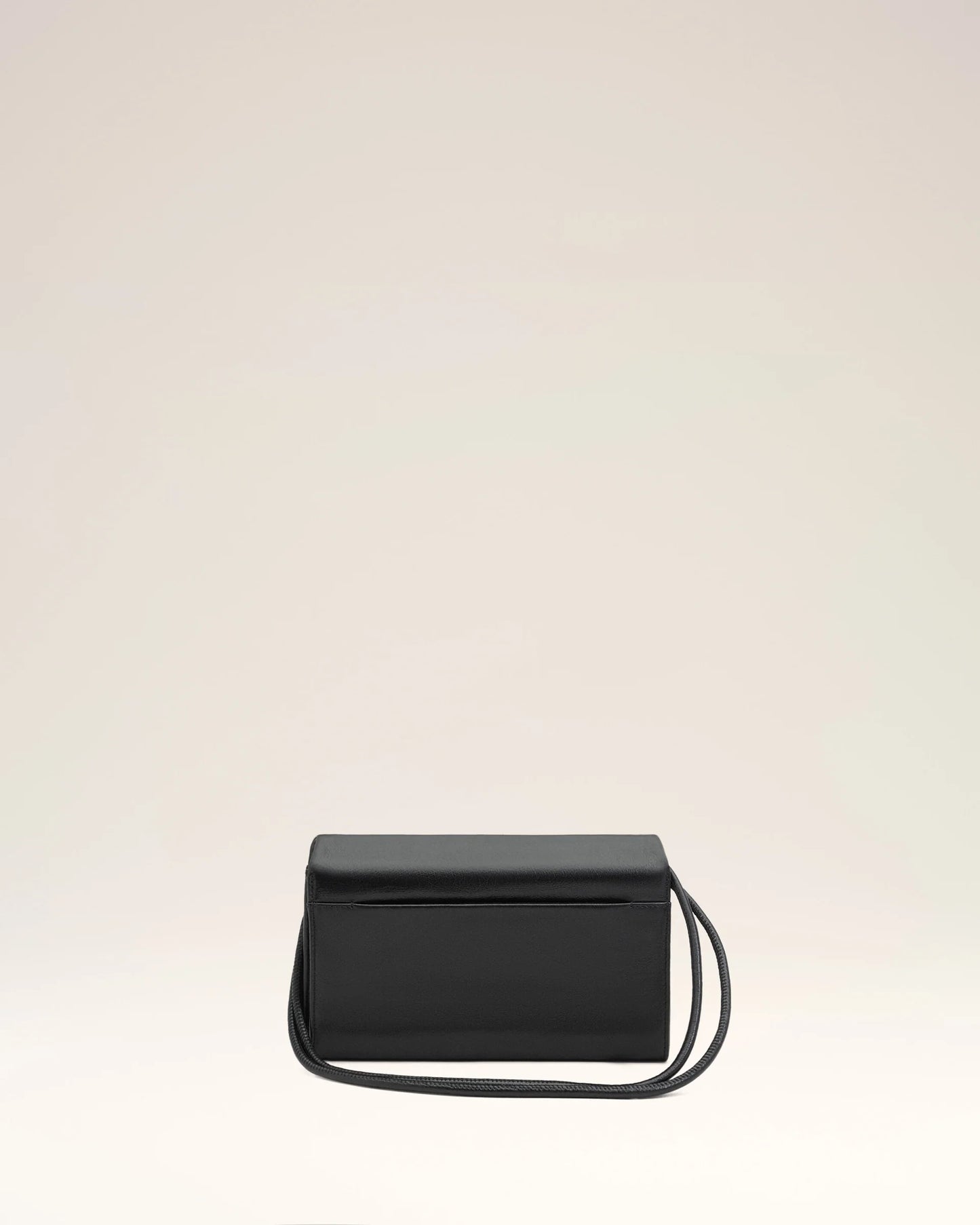 Person holding a black handbag against a neutral background