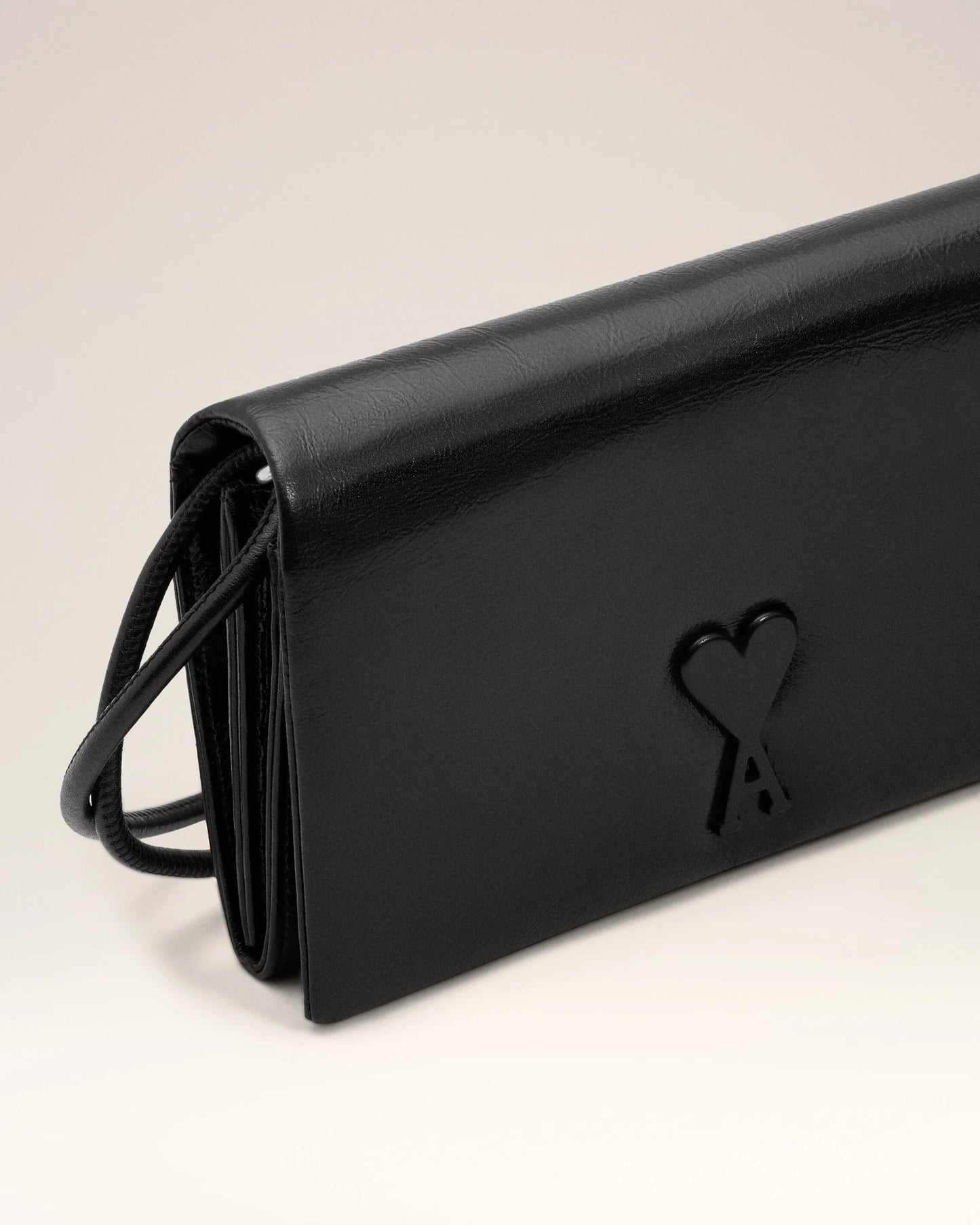 Person holding a black handbag against a neutral background