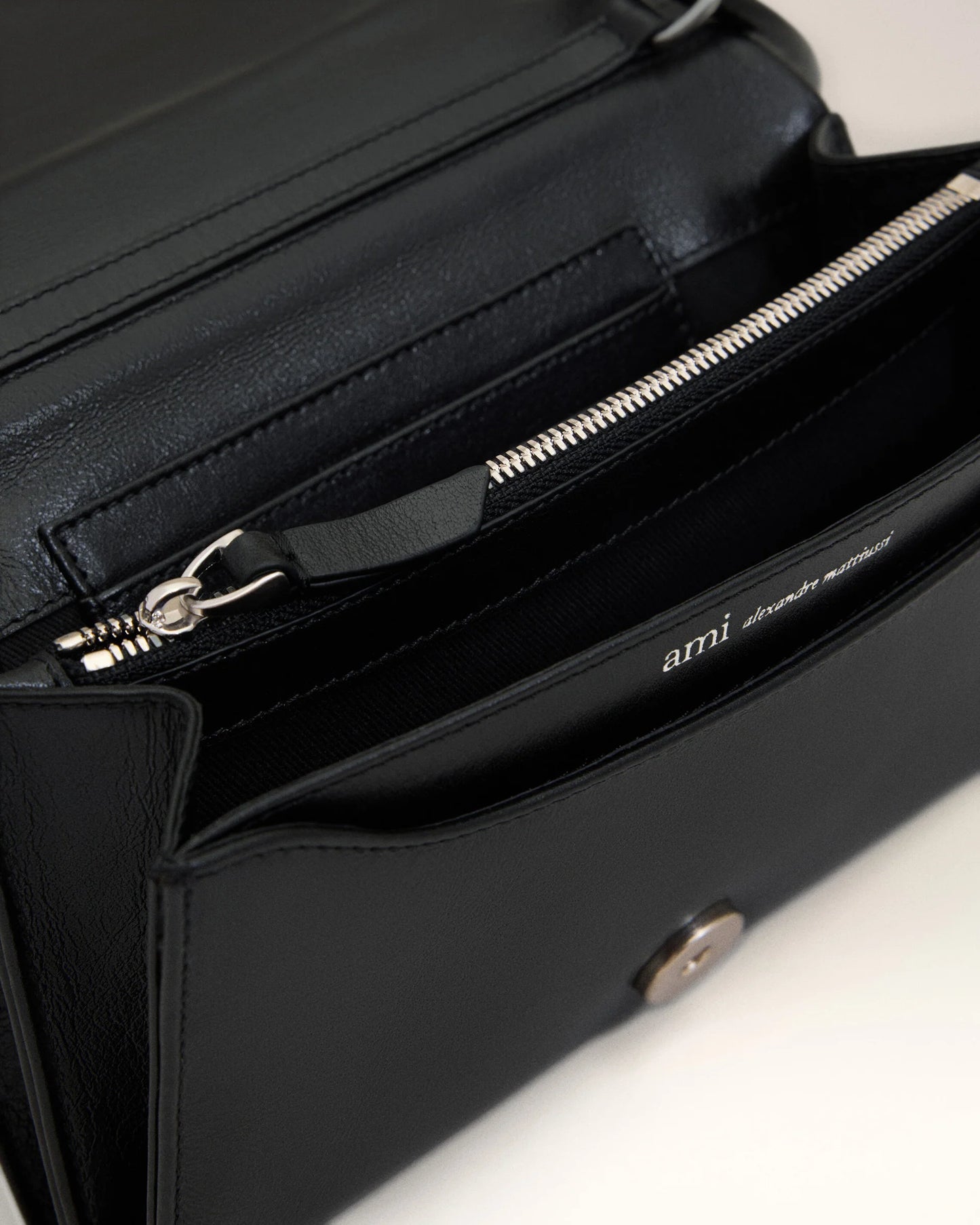 Person holding a black handbag against a neutral background