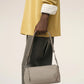 Light gray handbag with a heart detail on a light beige background ami paris