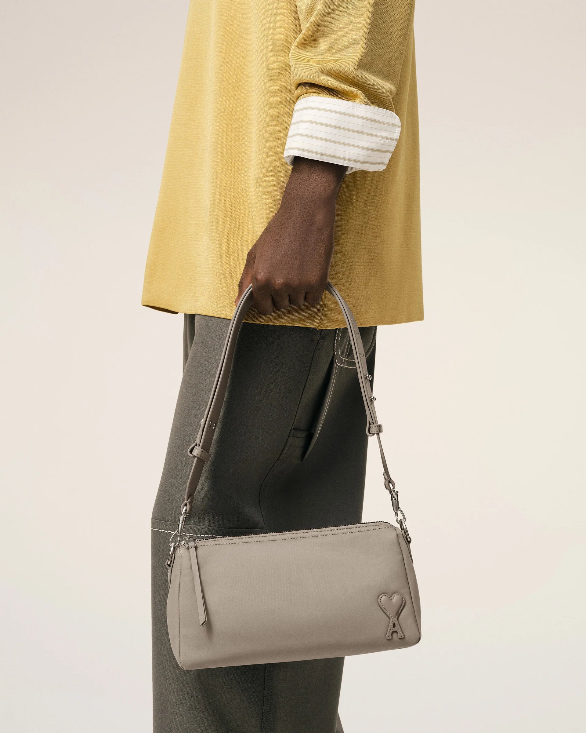Light gray handbag with a heart detail on a light beige background ami paris
