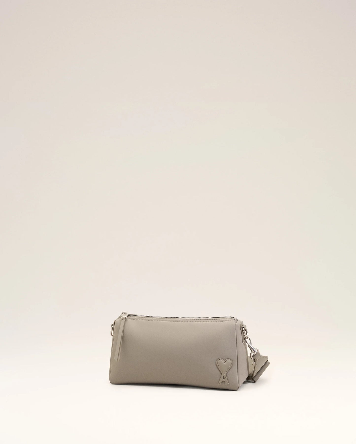 Light gray handbag with a heart detail on a light beige background ami paris