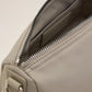 Light gray handbag with a heart detail on a light beige background ami paris
