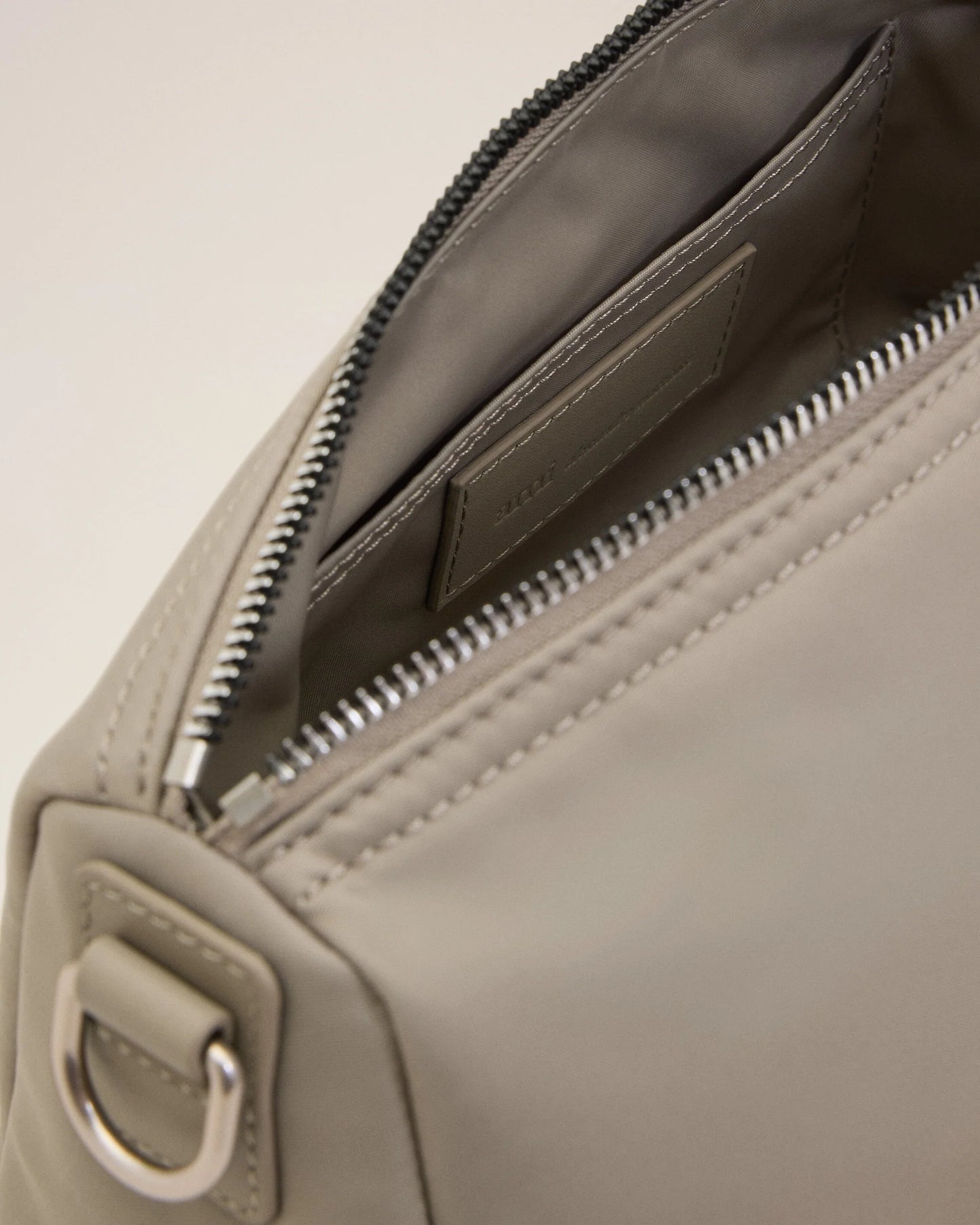 Light gray handbag with a heart detail on a light beige background ami paris