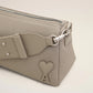 Light gray handbag with a heart detail on a light beige background ami paris