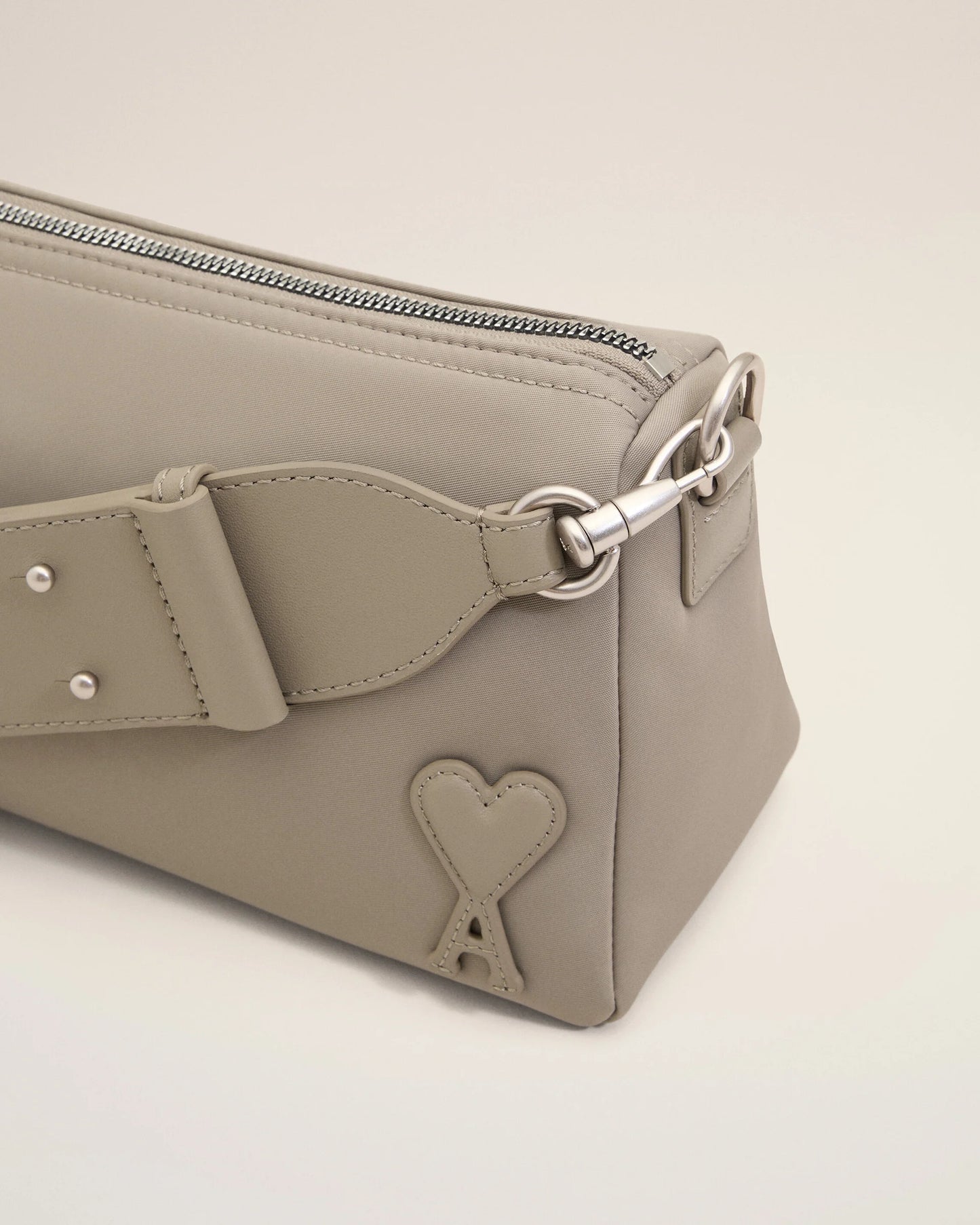 Light gray handbag with a heart detail on a light beige background ami paris