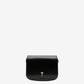 Black leather bag with a gold heart detail on a beige background