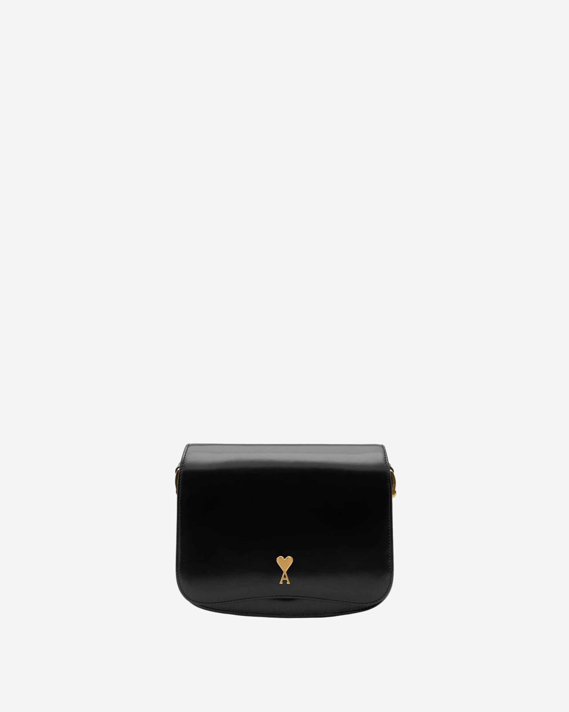 Black leather bag with a gold heart detail on a beige background
