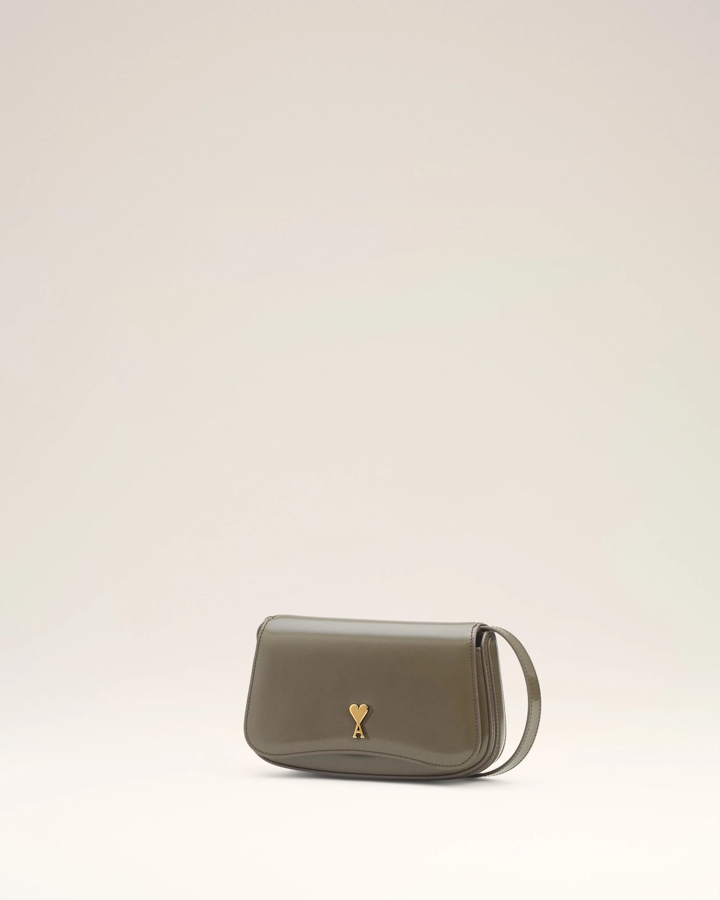 Green handbag with a gold heart emblem on a light beige background ami paris