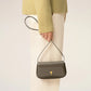 Green handbag with a gold heart emblem on a light beige background ami paris