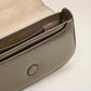 Green handbag with a gold heart emblem on a light beige background ami paris