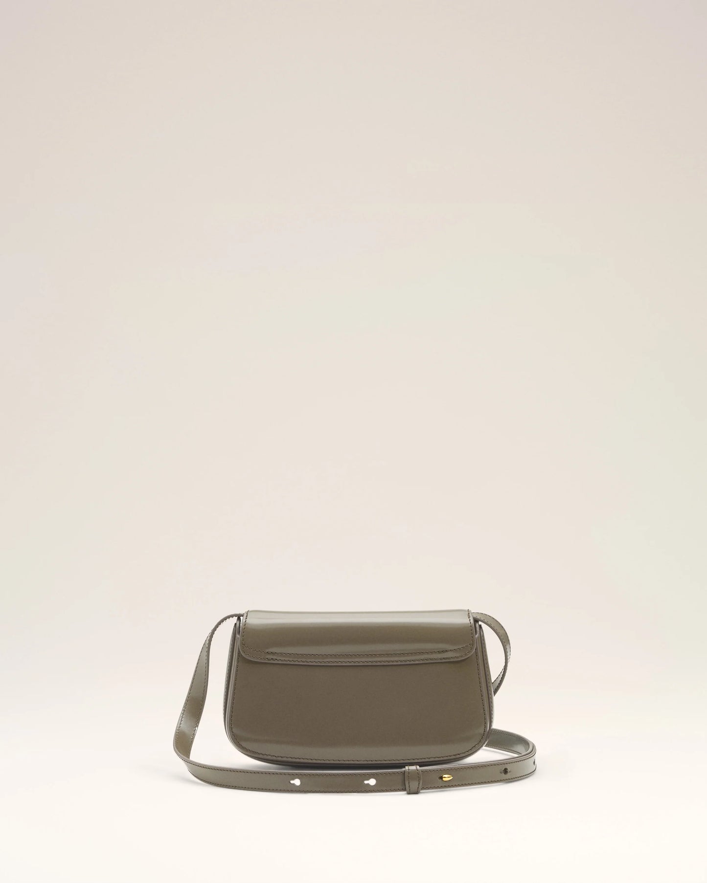 Green handbag with a silver flap on a light beige background green