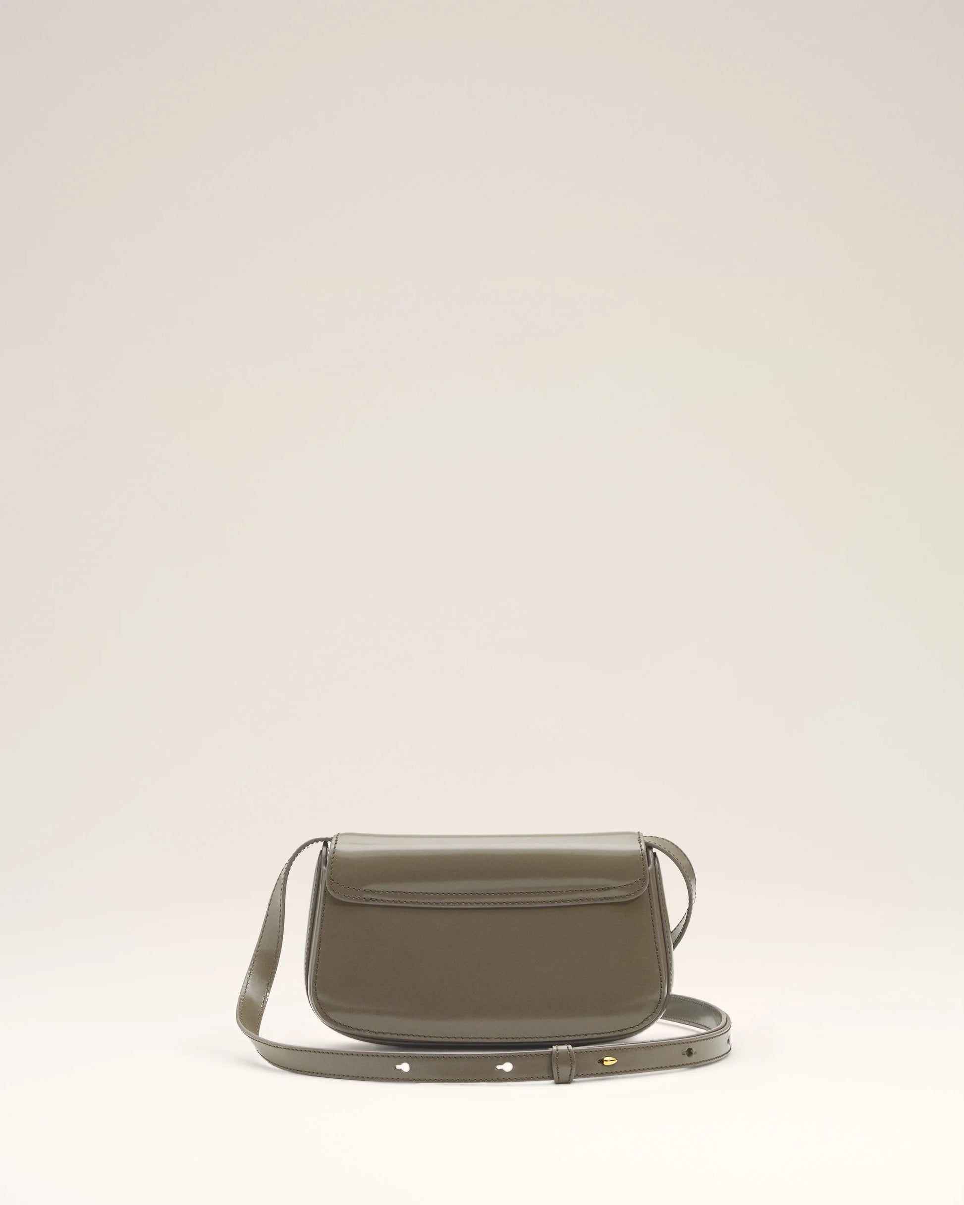 Green handbag with a silver flap on a light beige background green