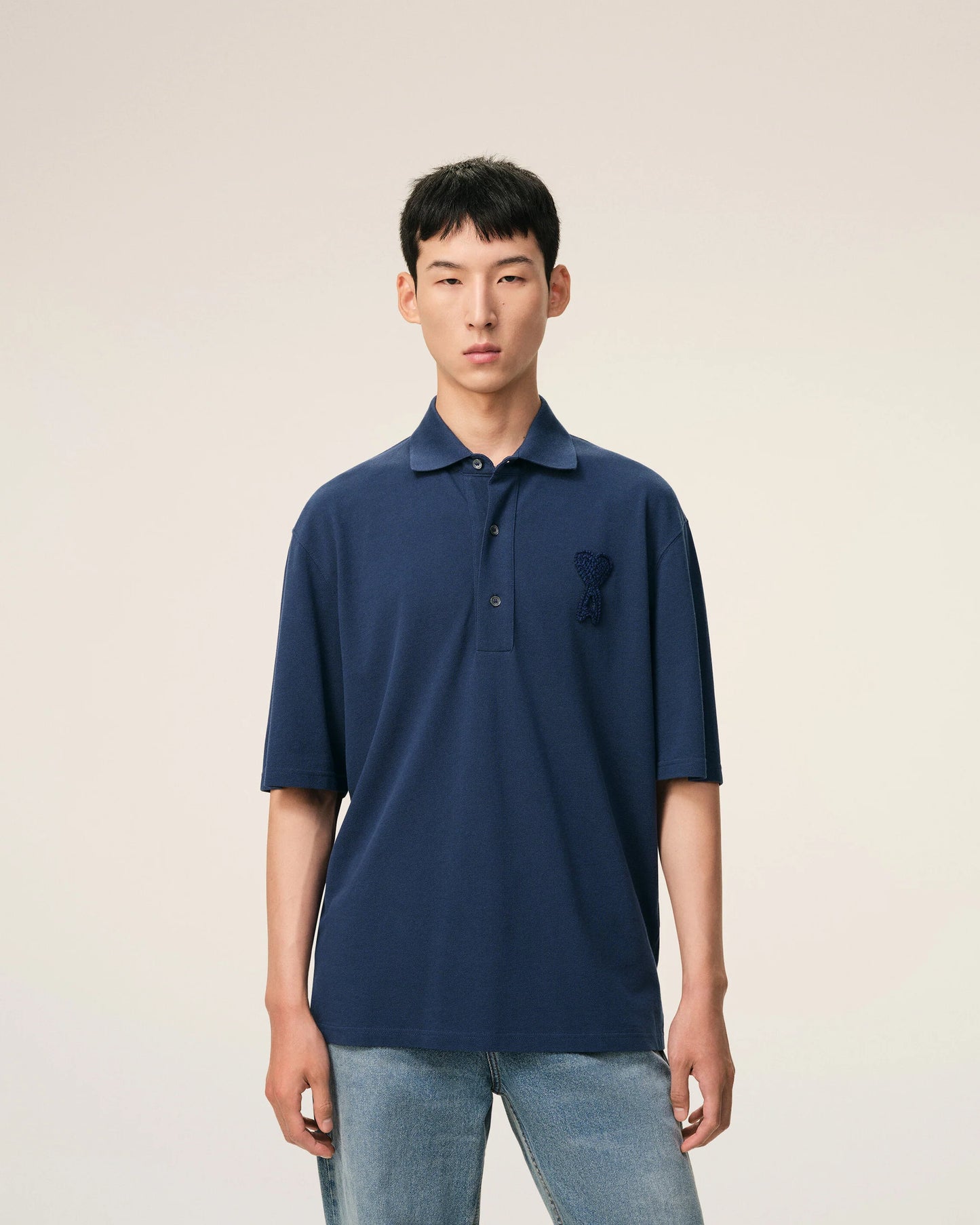 Navy blue polo shirt with a small logo on a beige background ami paris