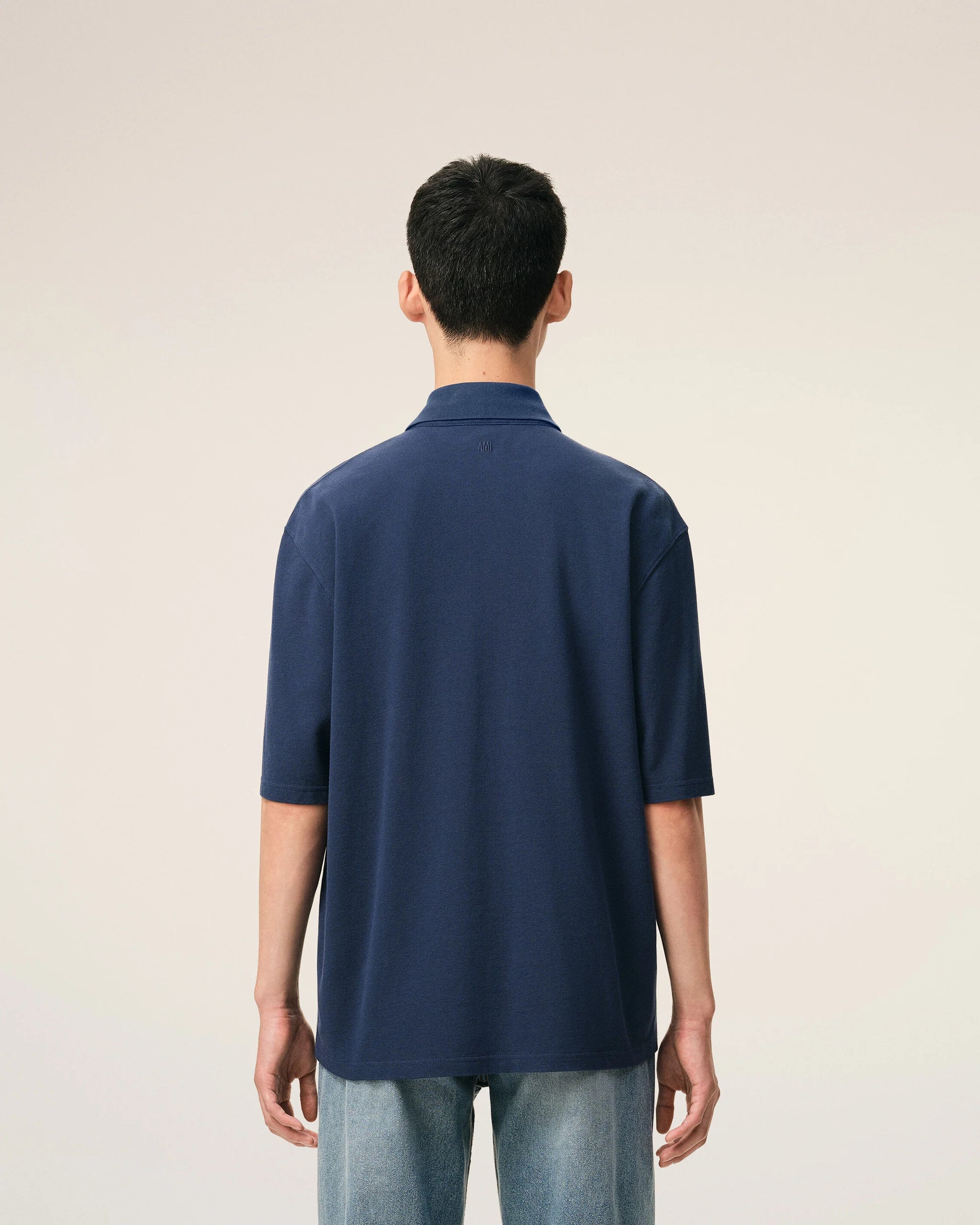 Navy blue polo shirt with a small logo on a beige background ami paris