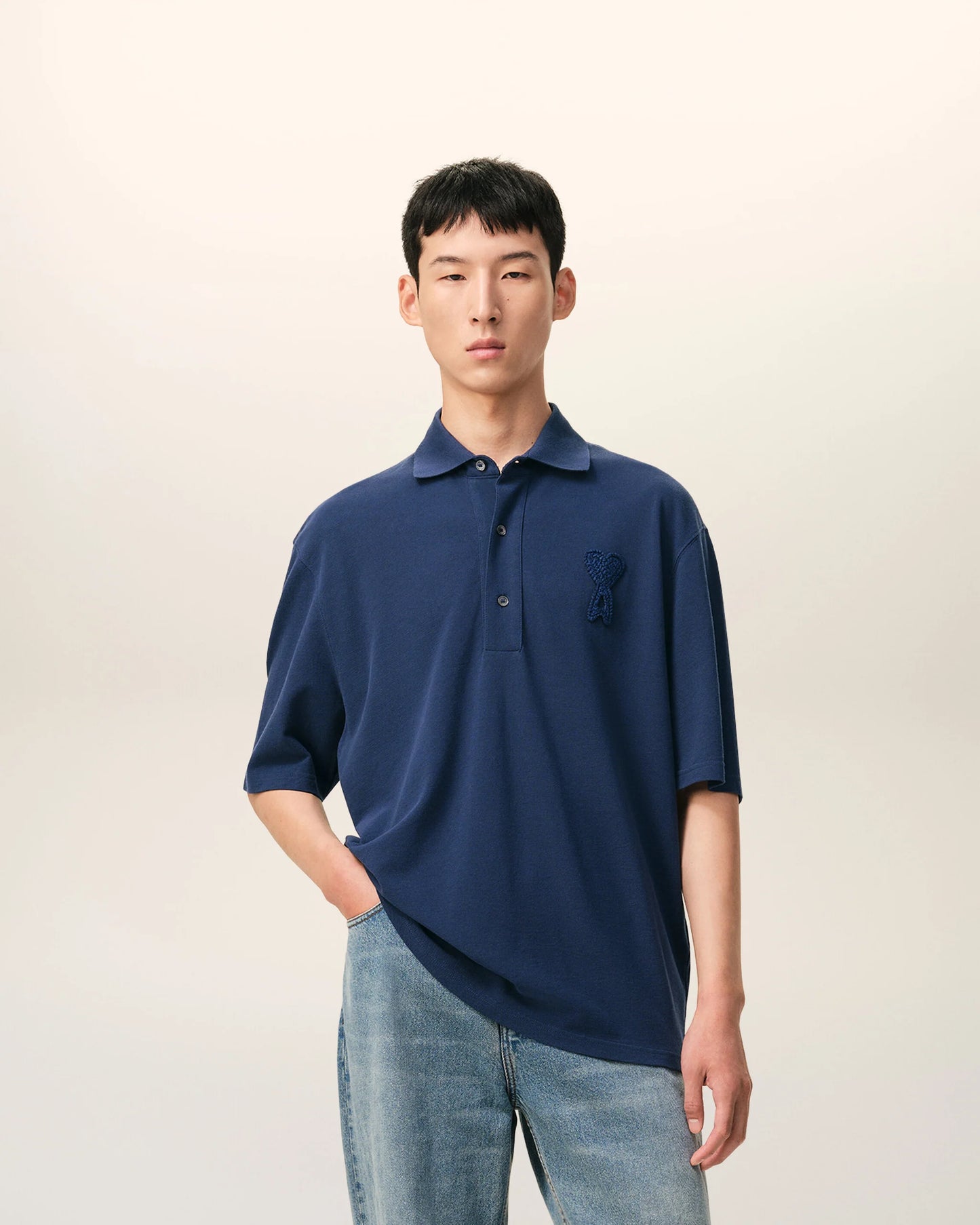 Navy blue polo shirt with a small logo on a beige background ami paris