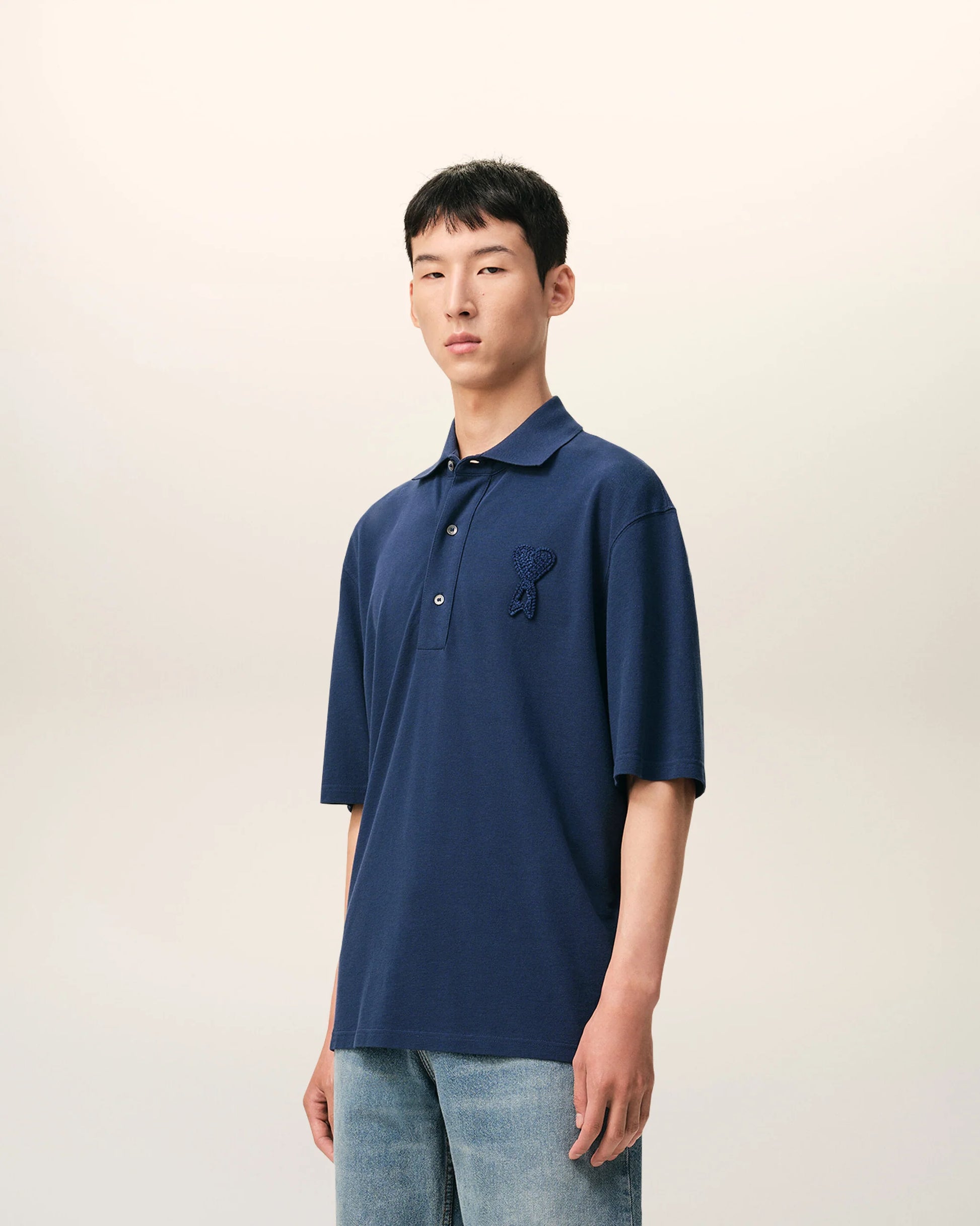 Navy blue polo shirt with a small logo on a beige background ami paris