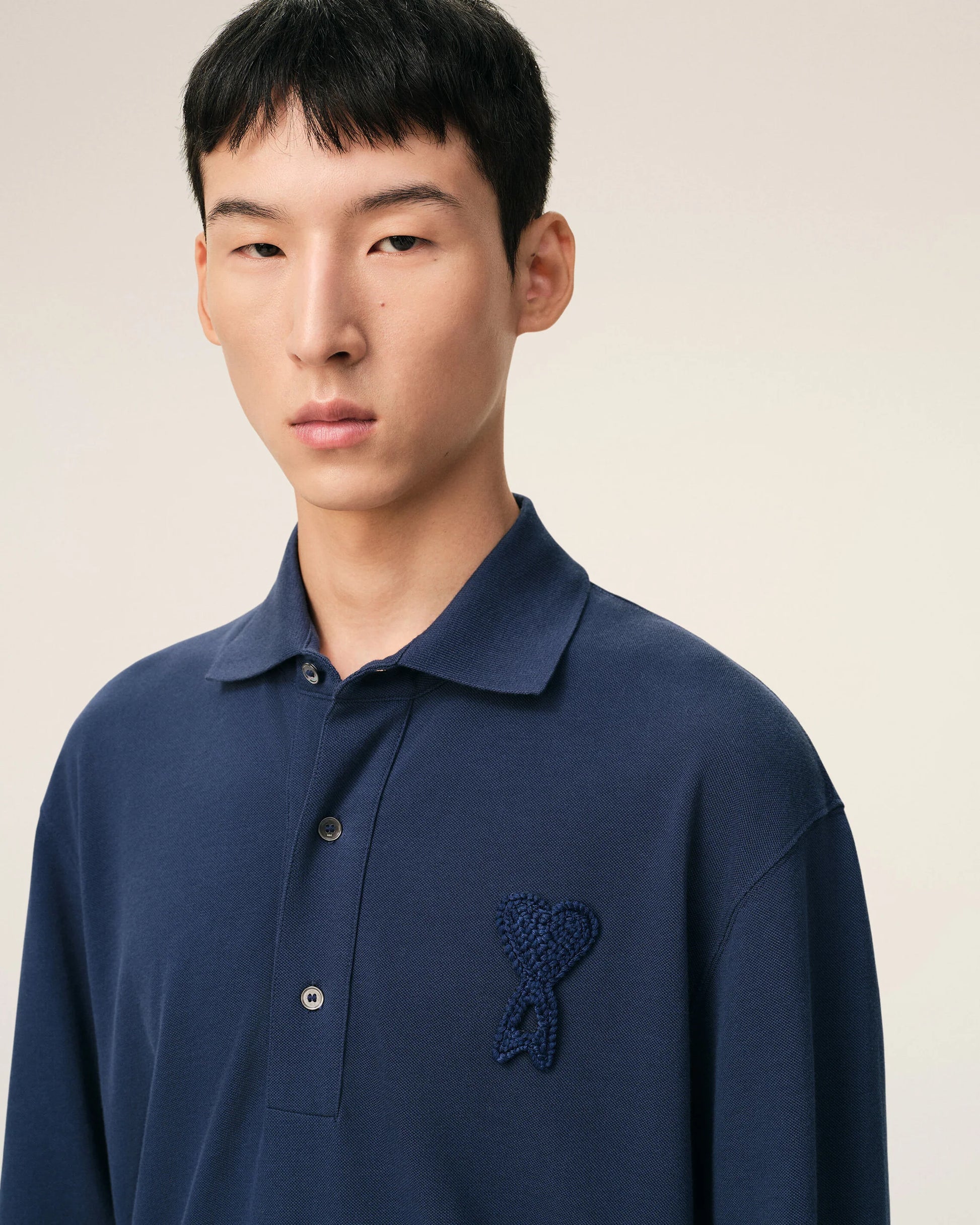Navy blue polo shirt with a small logo on a beige background ami paris