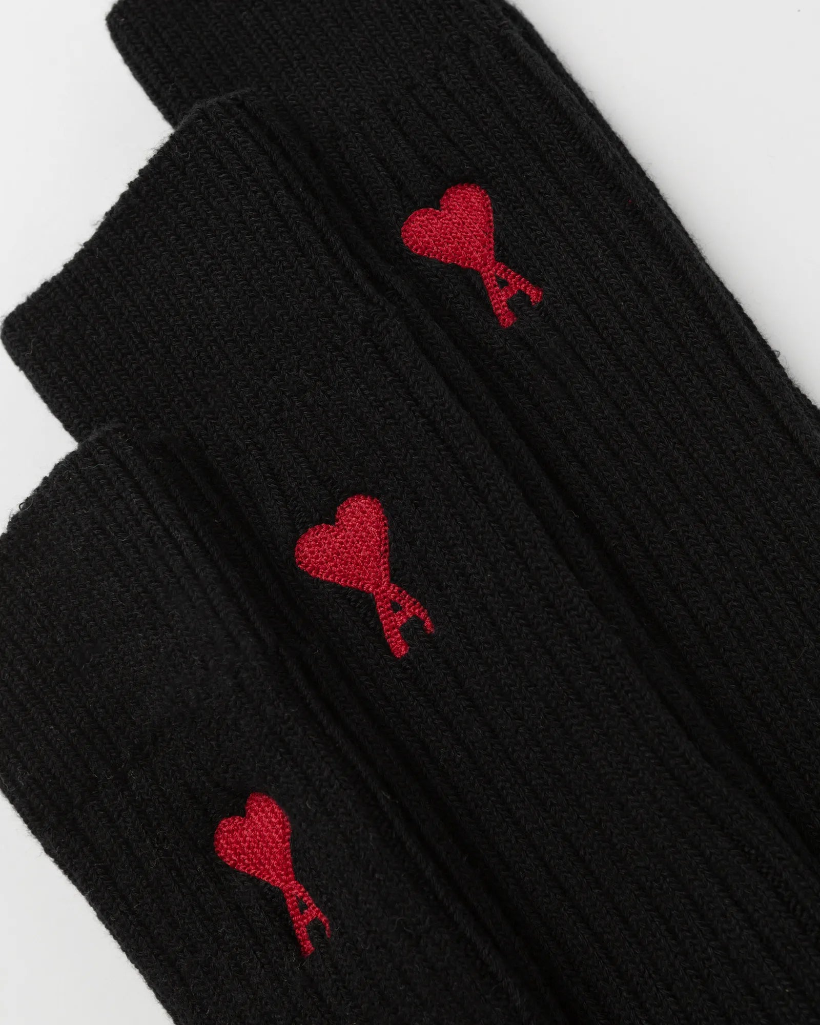 Black sock with a red heart design and 'ami' label on a light gray background
