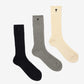 Three pairs of socks in beige, gray, and black on a light beige background