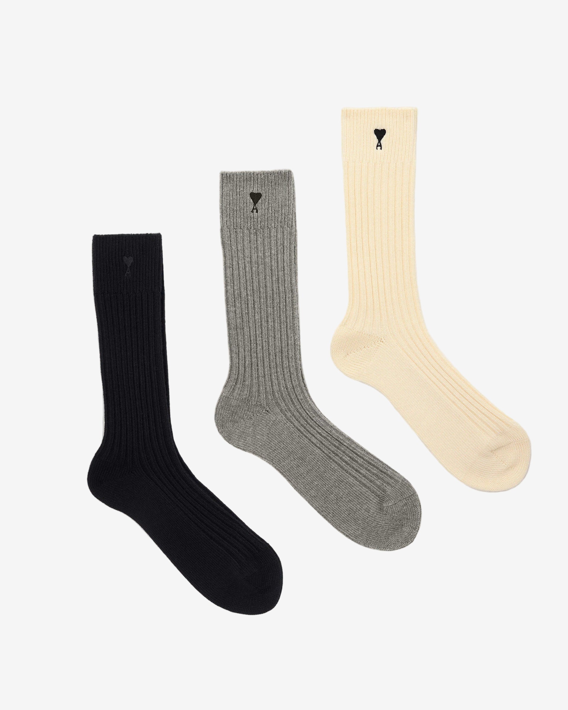 Three pairs of socks in beige, gray, and black on a light beige background