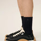 Three pairs of socks in beige, gray, and black on a light beige background