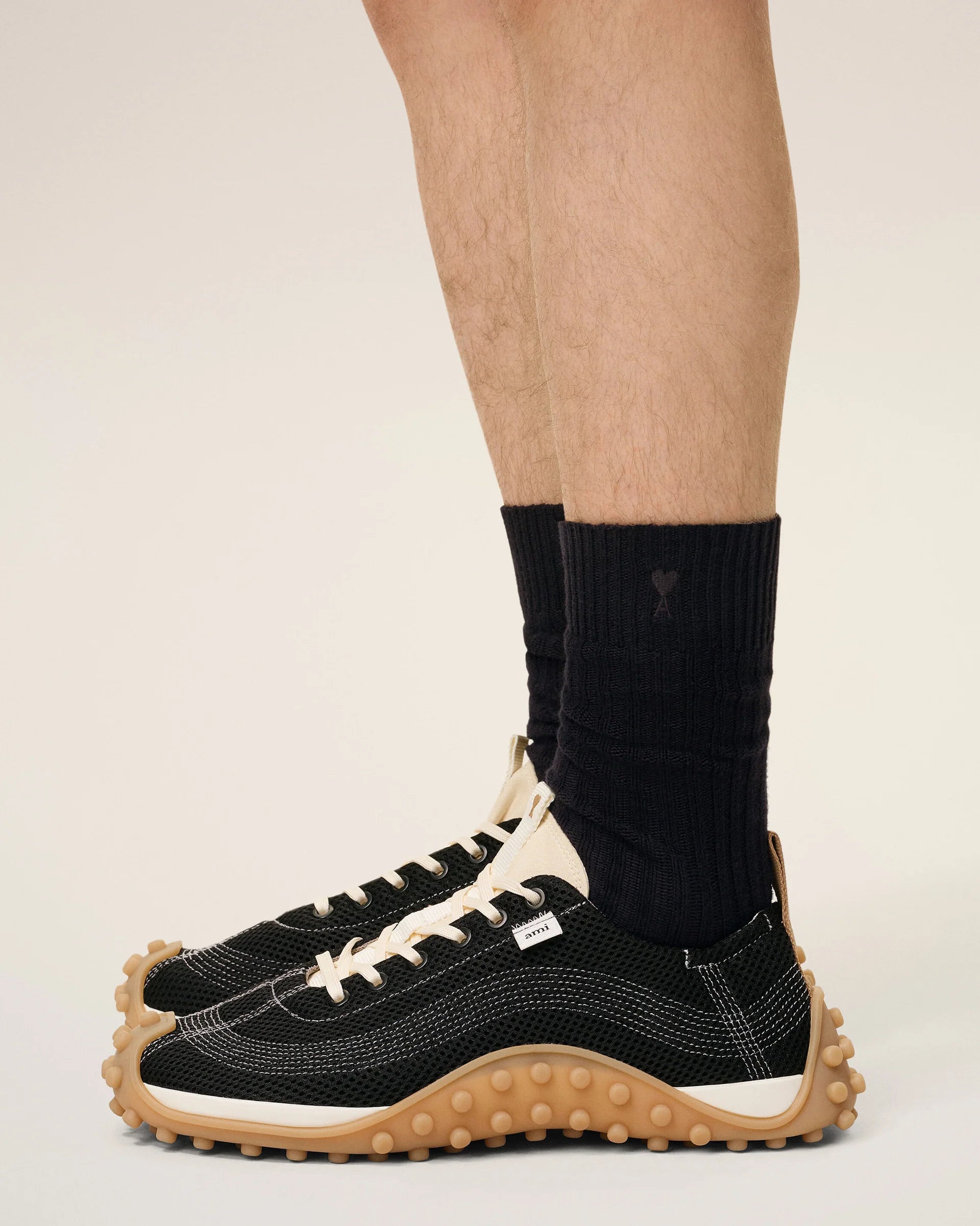 Three pairs of socks in beige, gray, and black on a light beige background