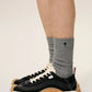 Three pairs of socks in beige, gray, and black on a light beige background
