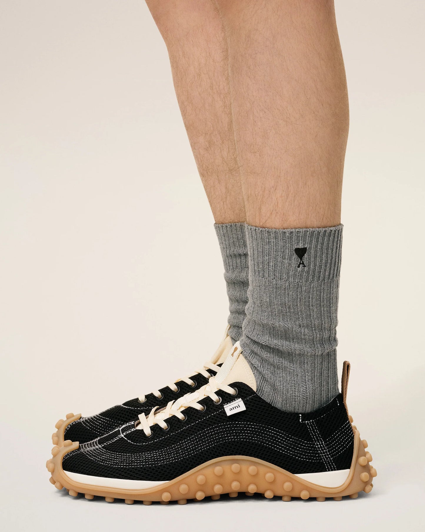 Three pairs of socks in beige, gray, and black on a light beige background