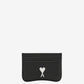 Black cardholder with a white logo on a beige background