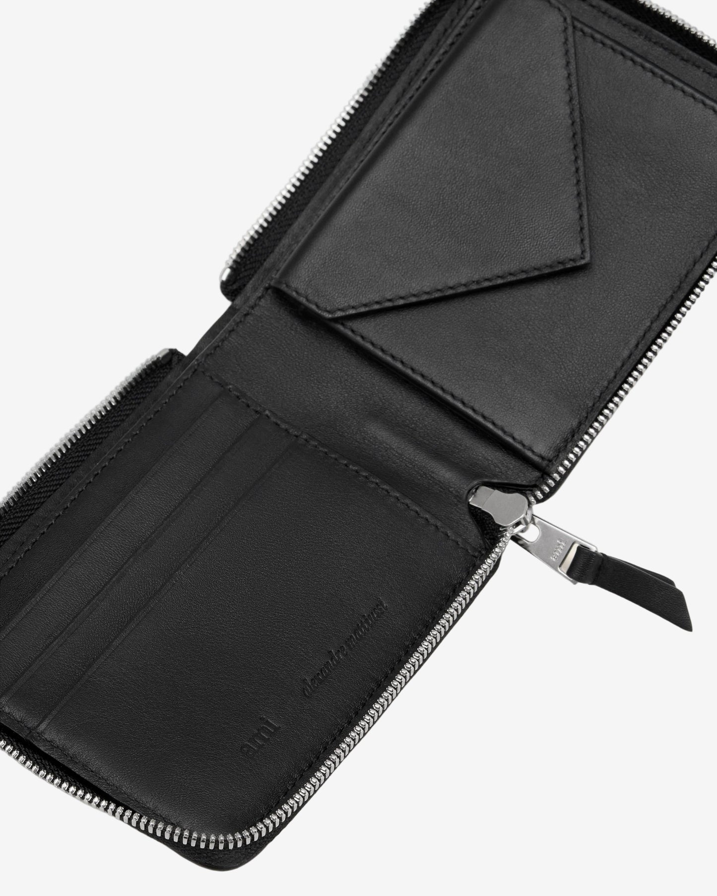 Black leather wallet with zipper on a light beige background