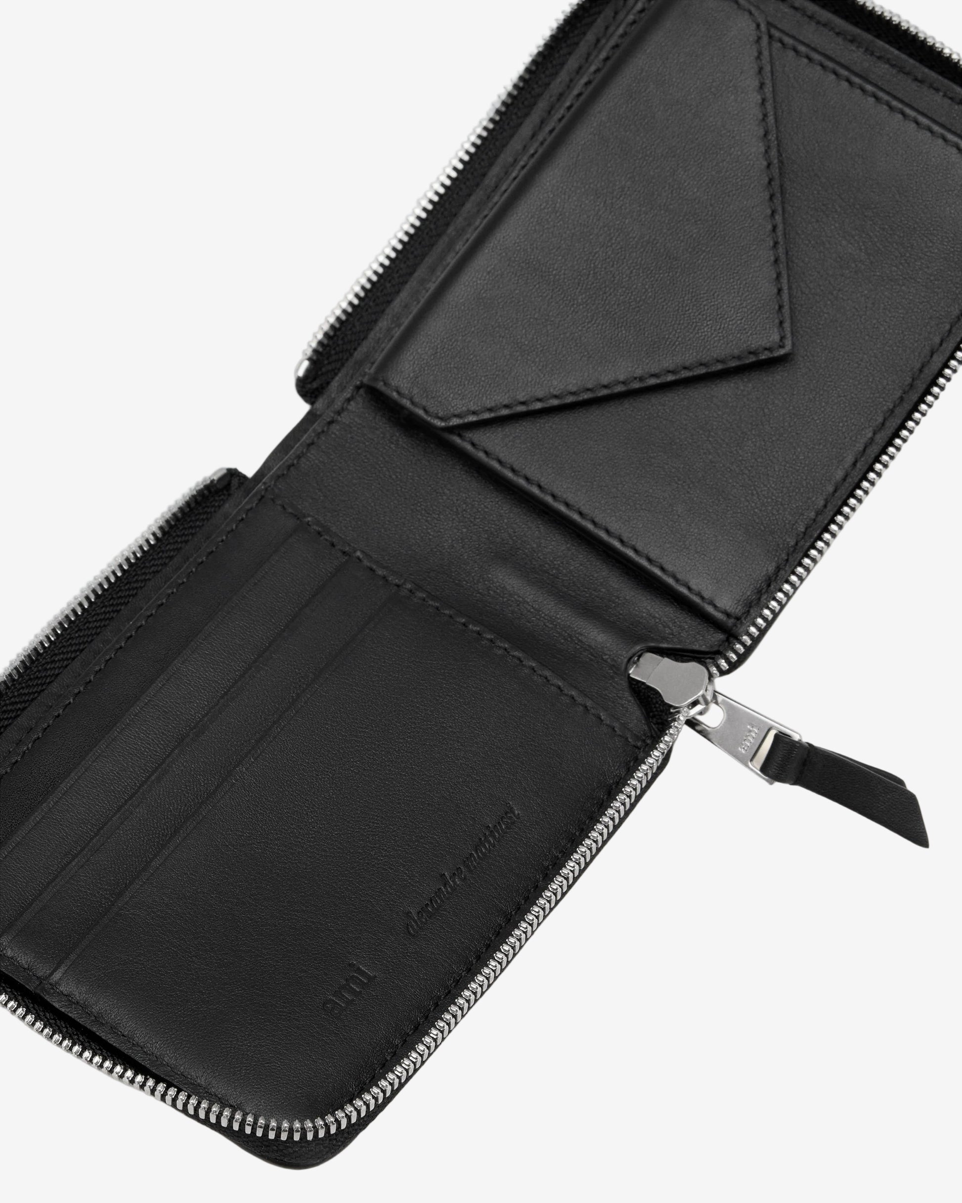 Black leather wallet with zipper on a light beige background