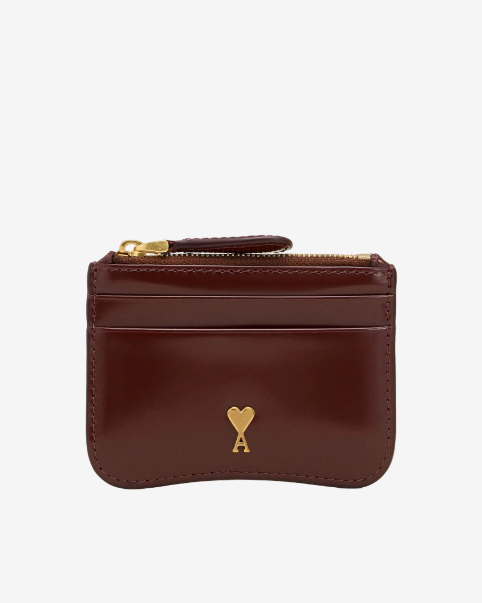 Brown leather wallet with gold zipper and heart emblem on a beige background