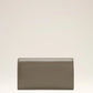 Green wallet with a small logo on a beige background