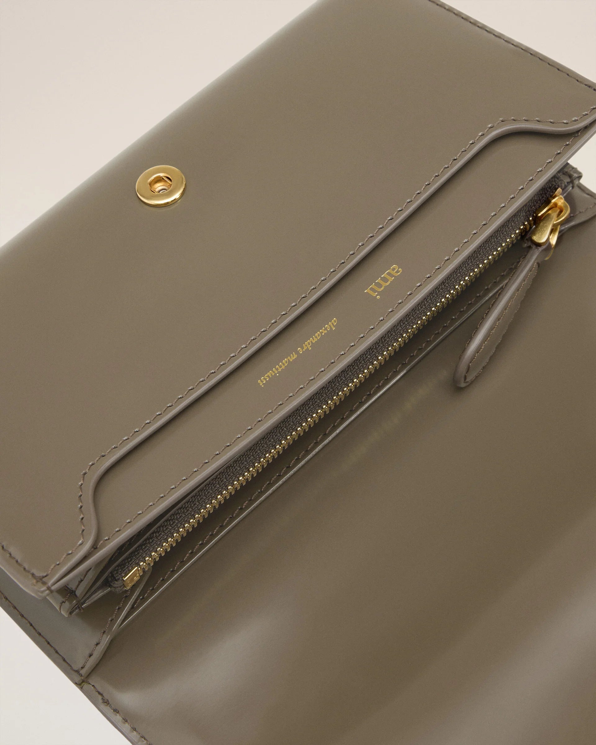 Green wallet with a small logo on a beige background