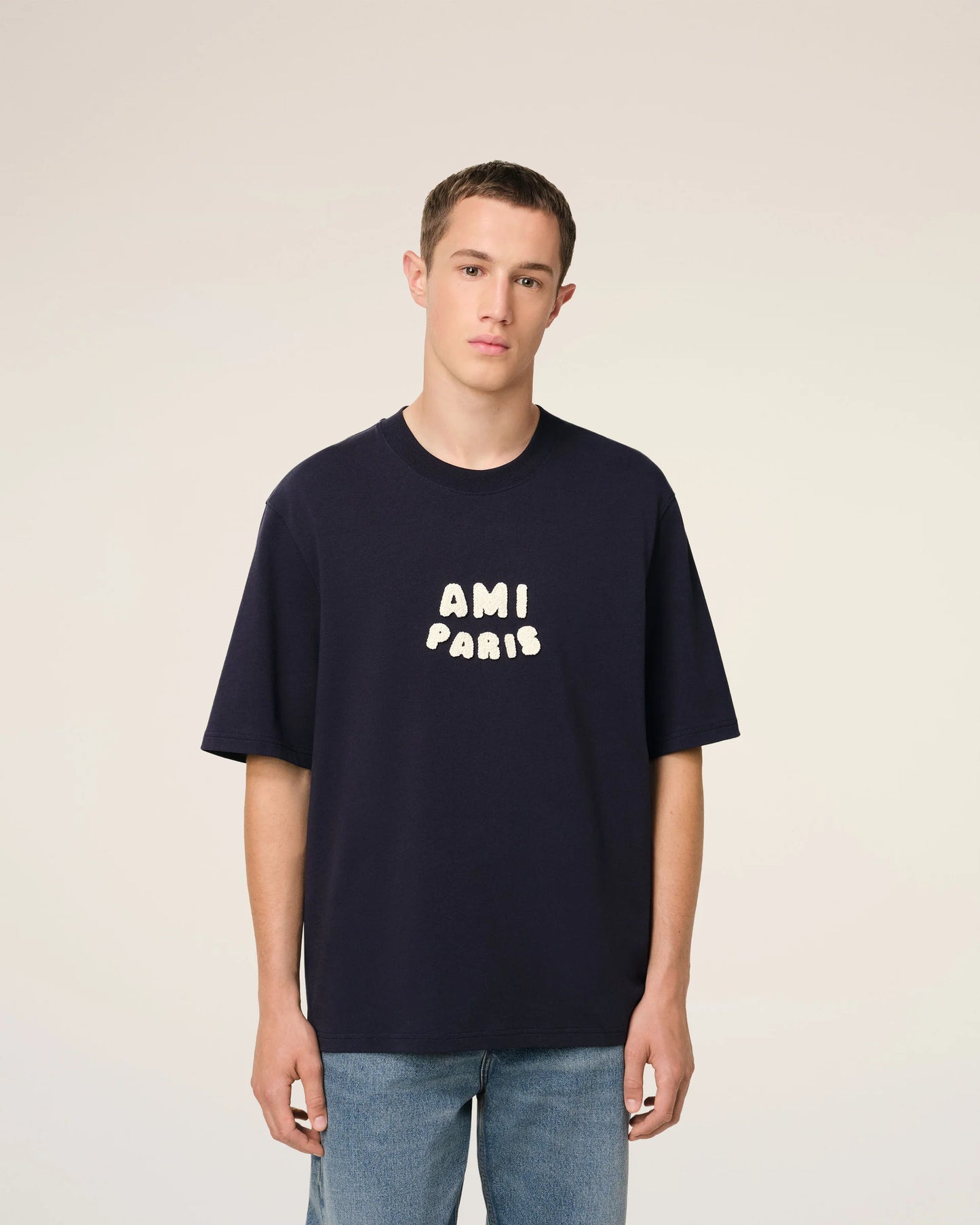 Navy blue t-shirt with 'AMI PARIS' text on a light gray background