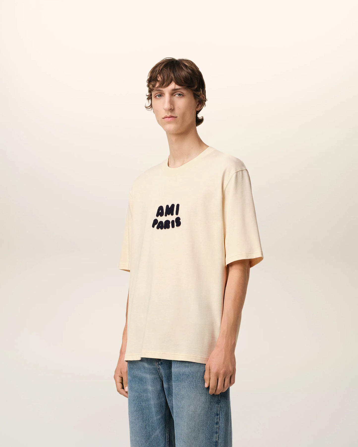Beige t-shirt with 'AM! PARIS' text on a light gray background