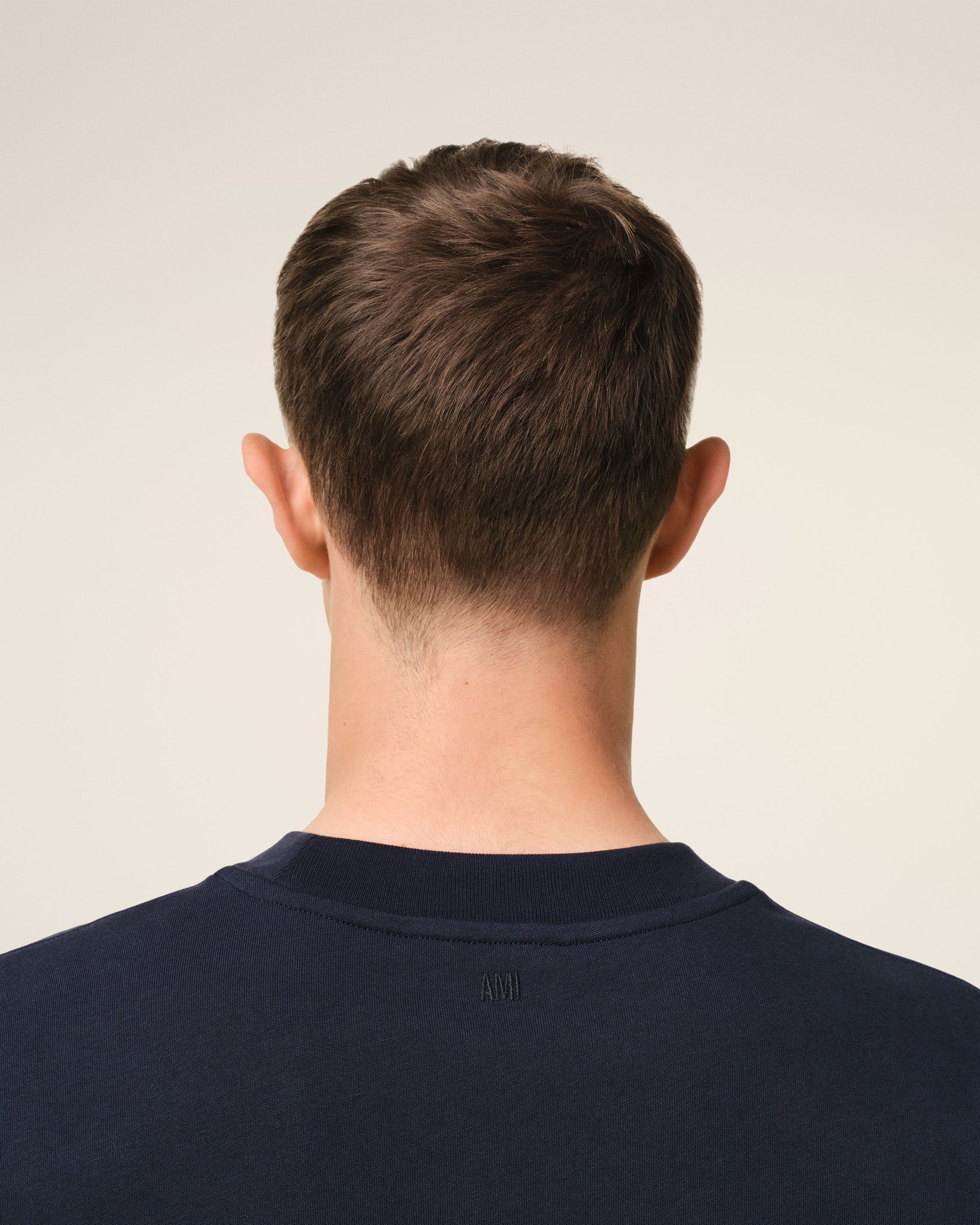 Navy blue t-shirt with 'AMI PARIS' text on a light gray background
