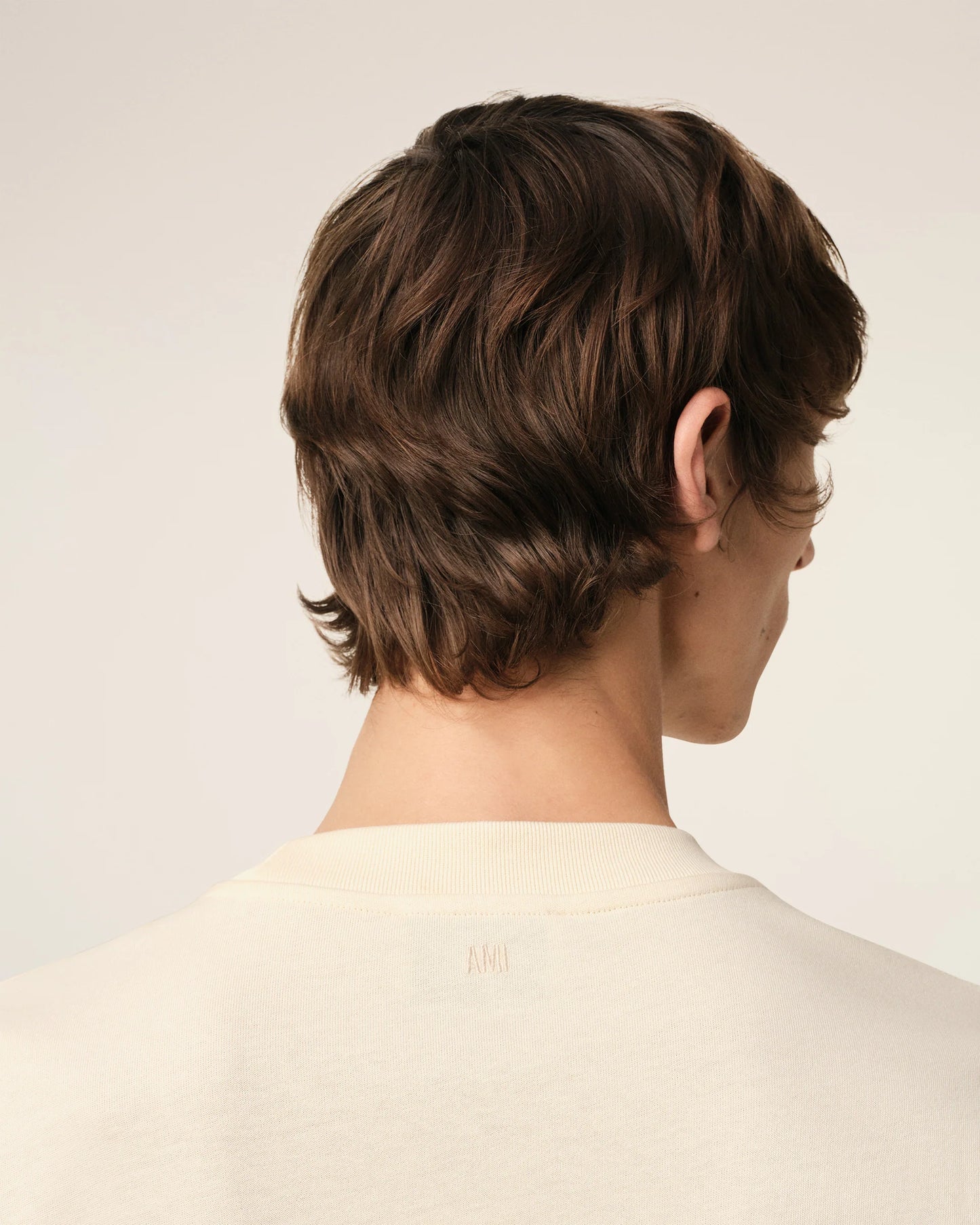 Beige t-shirt with 'AM! PARIS' text on a light gray background