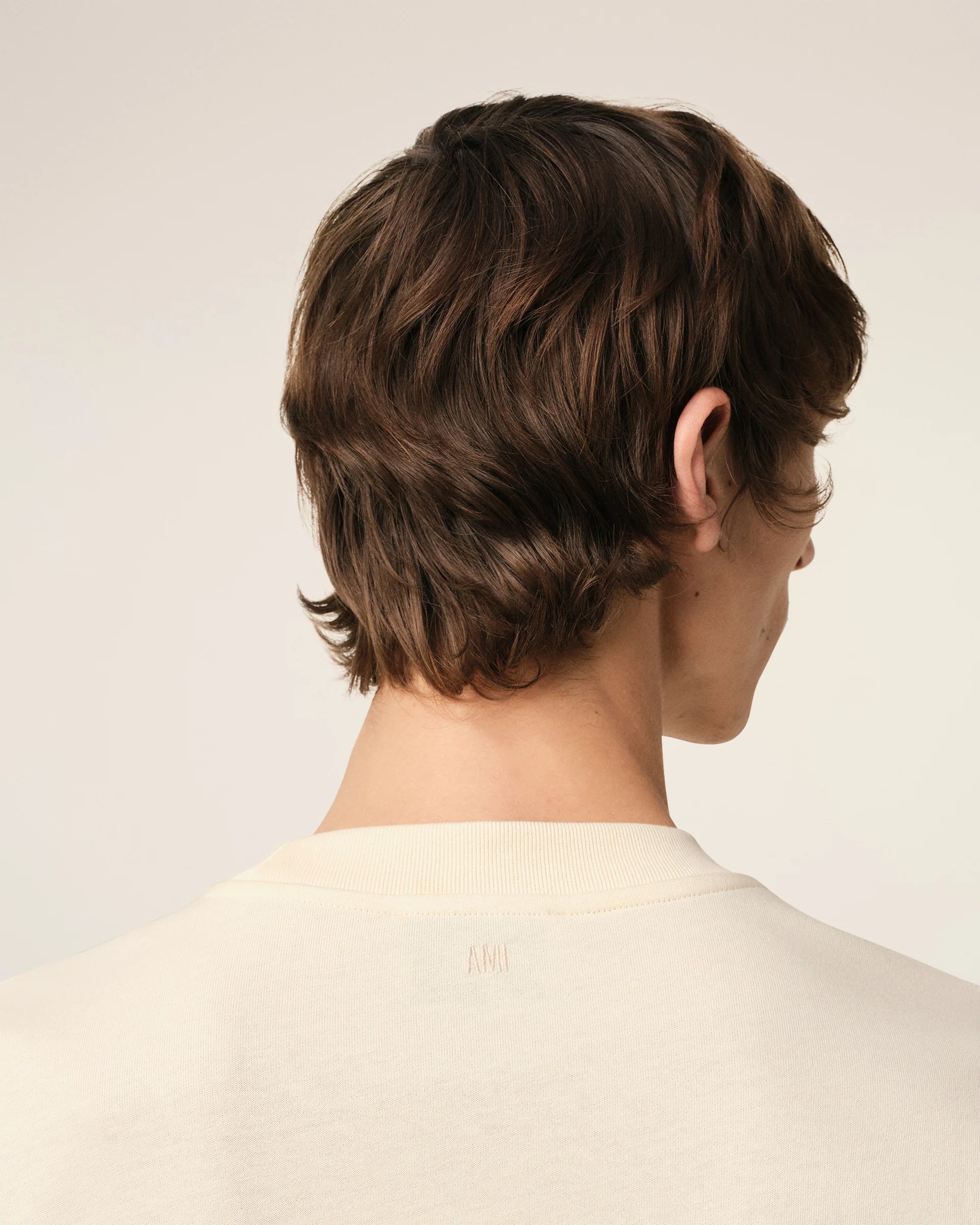 Beige t-shirt with 'AM! PARIS' text on a light gray background