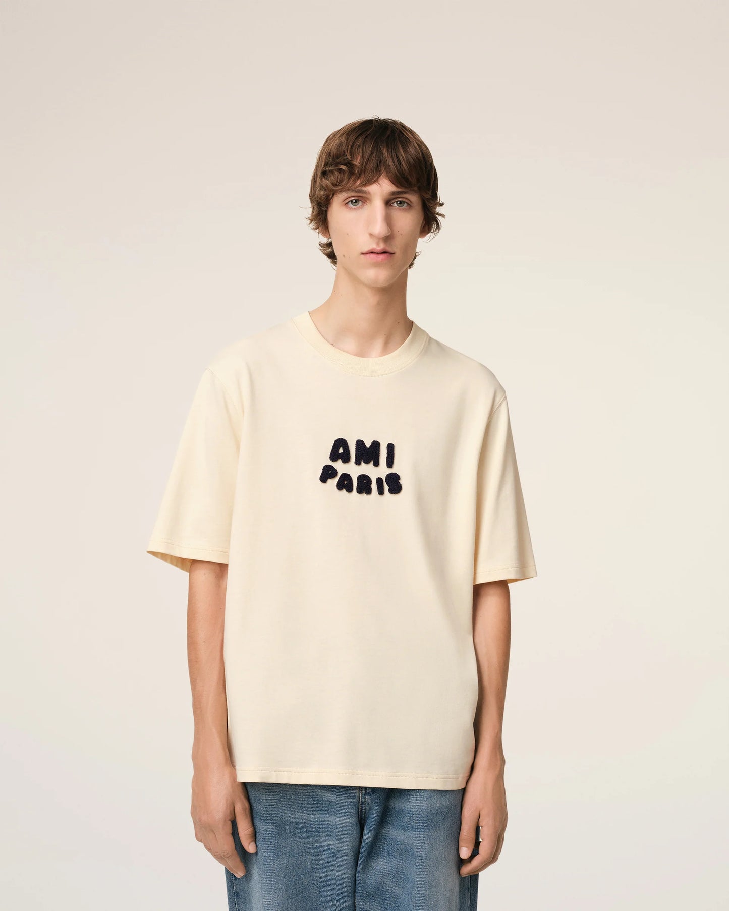 Beige t-shirt with 'AM! PARIS' text on a light gray background