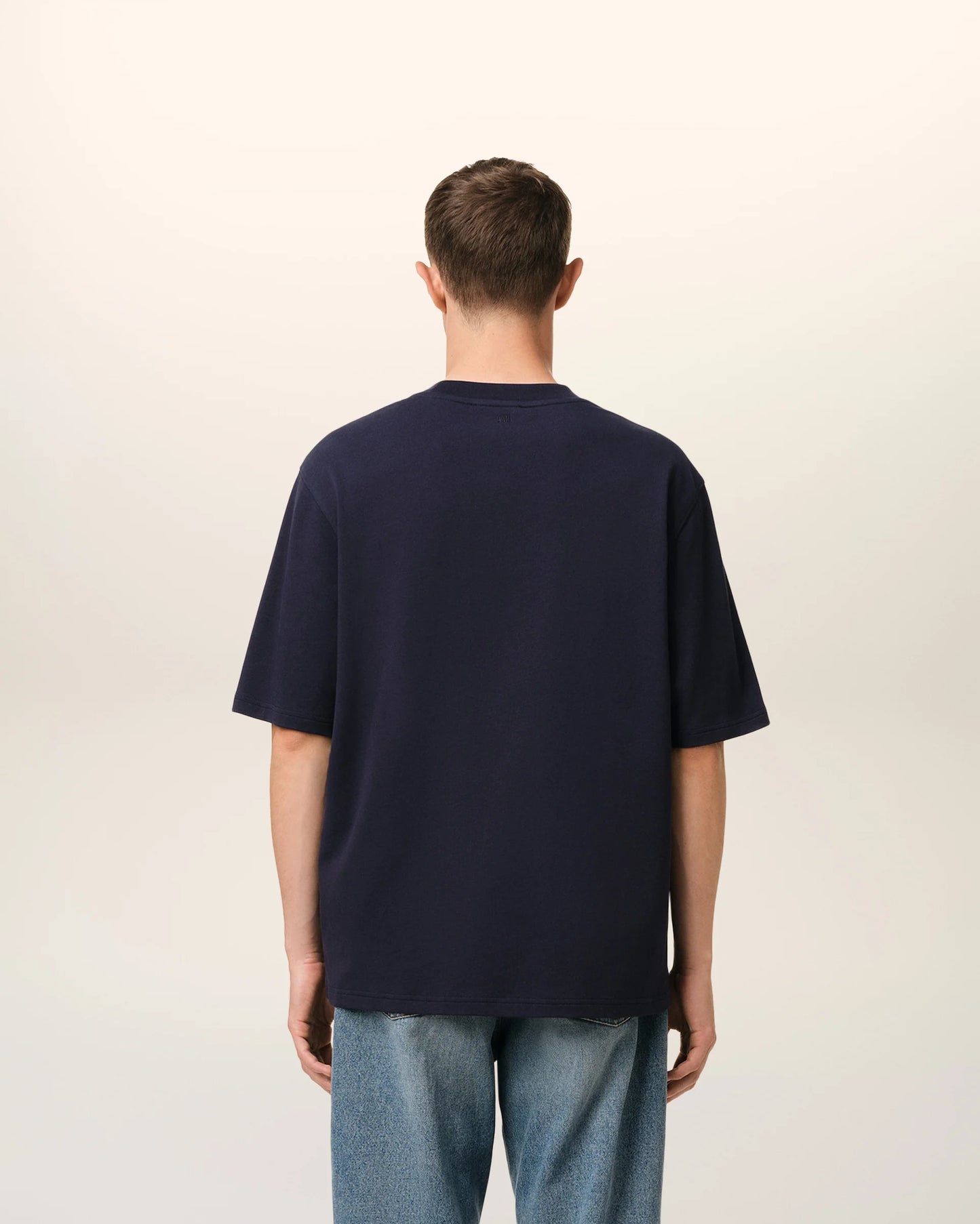 Navy blue t-shirt with 'AMI PARIS' text on a light gray background